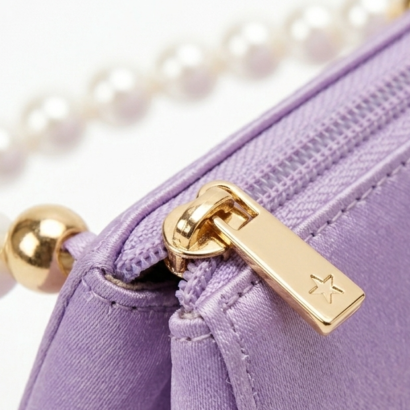 Close-up of gold-tone star zipper pull and high-sheen lavender satin texture