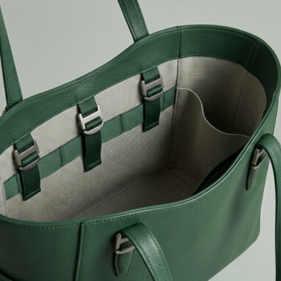 Inside of a leather tote bag showing canvas lining, tech webbing, and organization pockets.